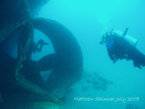 Divers swimming through the prop shaft of the Tasman Hauler wreck.