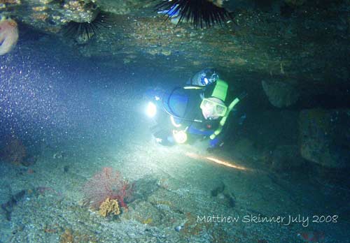 A diver wriggling out the end of the sea cave.